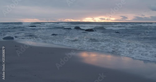 Waves on sandy beach on coast at sunset photo