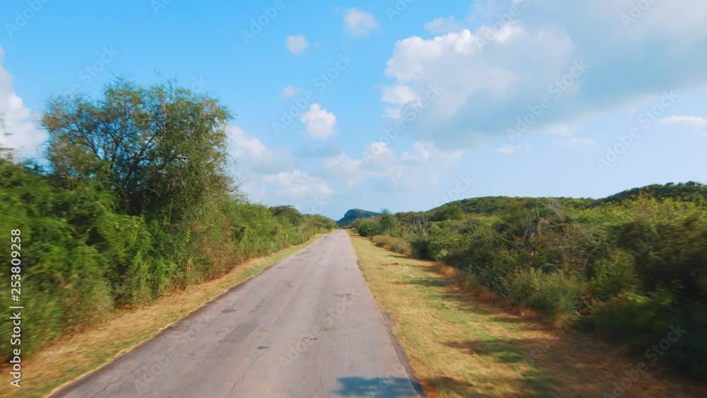 Driving down a rough and patched up rural road in Curacao, Caribbean Driving down a rough and patched up rural road in Curacao, Caribbean