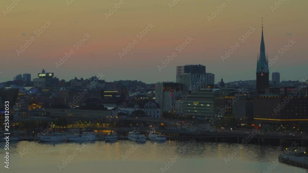 an outwards zooming sunset shot of bay in Stockholm where ferries are moored and with traffic and city in background. an outwards zooming sunset shot of bay in Stockholm where ferries are moored and with traffic and city in background.