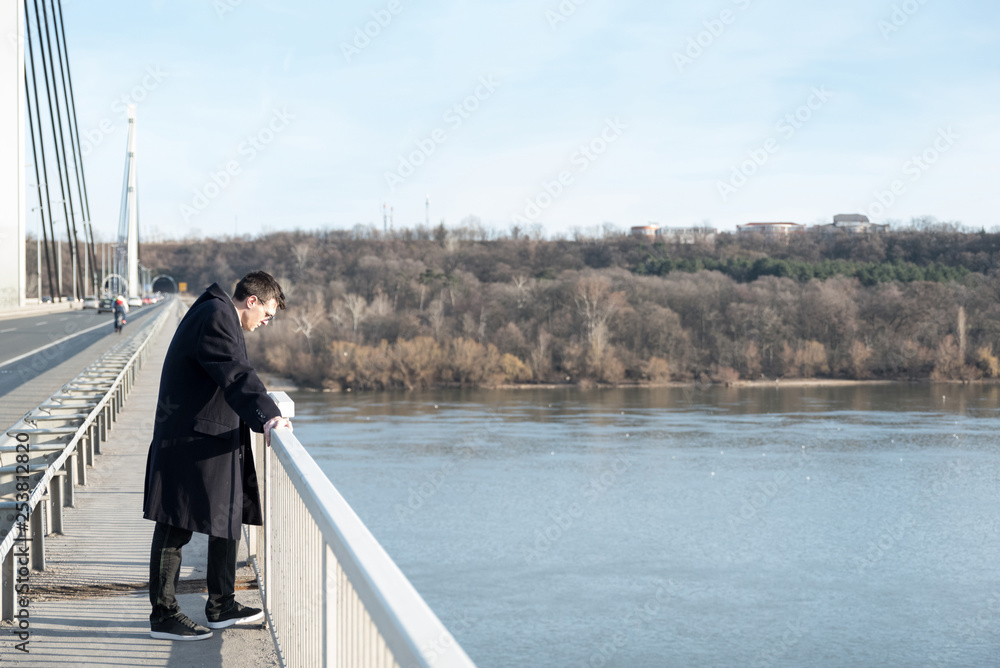 Lonely depressed and anxious man standing on the bridge with suicidal thoughts disappointed in people looking down prepared to jump in the water and end his life with suicide 