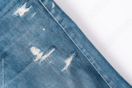 Close up picture of Textures ripped torn denim light blue jeans textile fabric background.