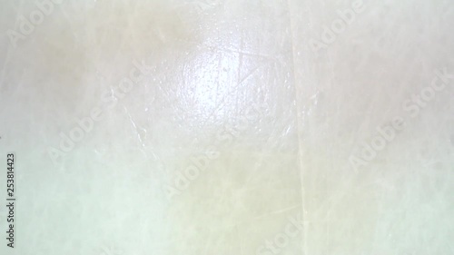 Hockey puck spins and falls on the ice in slow motion and stick hitting it, top view