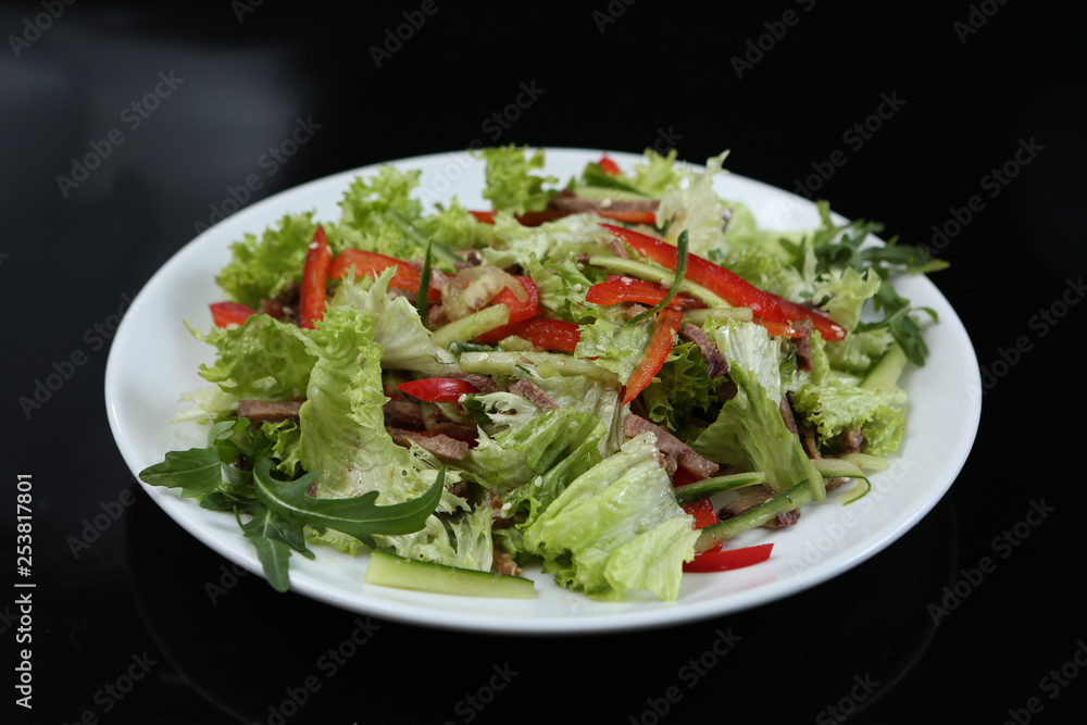 restaurant dish, green salad with cucumbers, red pepper, bacon and arugula, healthy food, close-up, for the menu