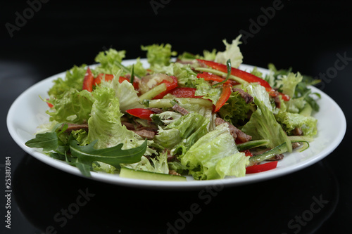 restaurant dish, green salad with cucumbers, red pepper, bacon and arugula, healthy food, close-up, for the menu
