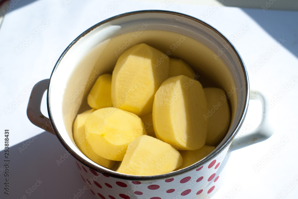 peeled raw potatoes in a pot on a white background peeled raw potatoes in a pot on a white background