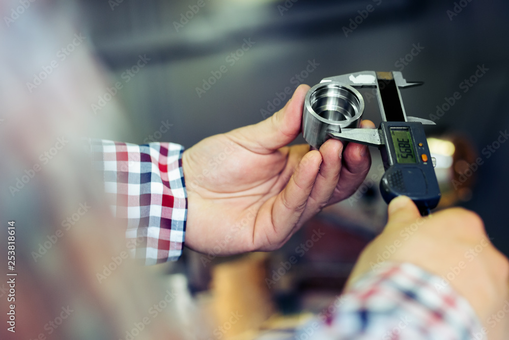 Naklejka premium Technician in a Metal Manufacturing Company Measuring with Digital Vernier Caliper 