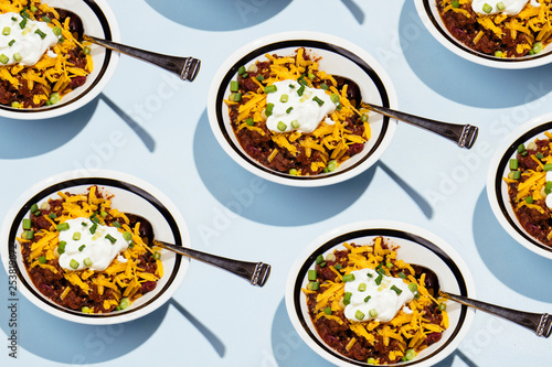Pattern of bowls of chili with cheese, chives and sour cream