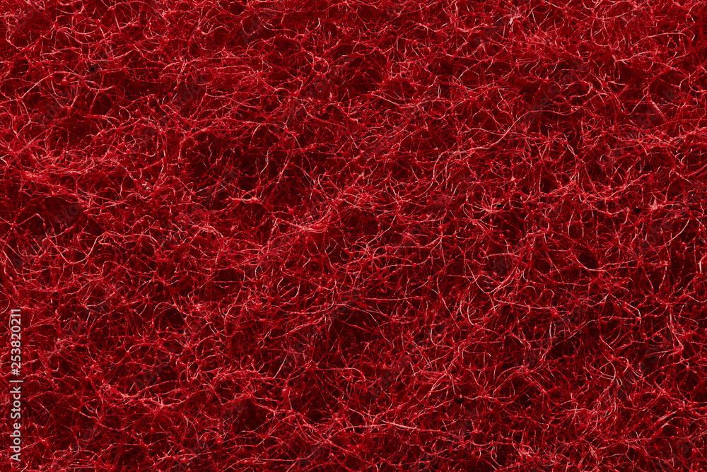 The texture of the surface of interwoven red threads of abrasive synthetic fiber. The texture of the surface of interwoven red threads of abrasive synthetic fiber.
