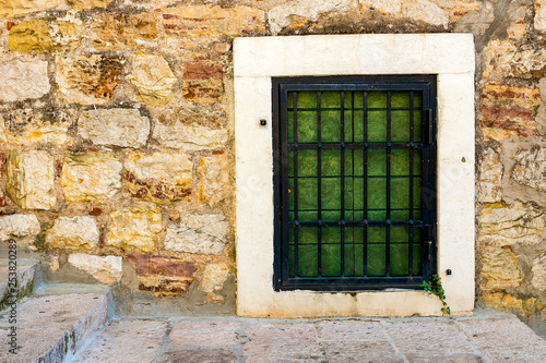 Authentic  stone wall  with beautiful  old  wooden shutters and window  minimal style  bright colors  background.