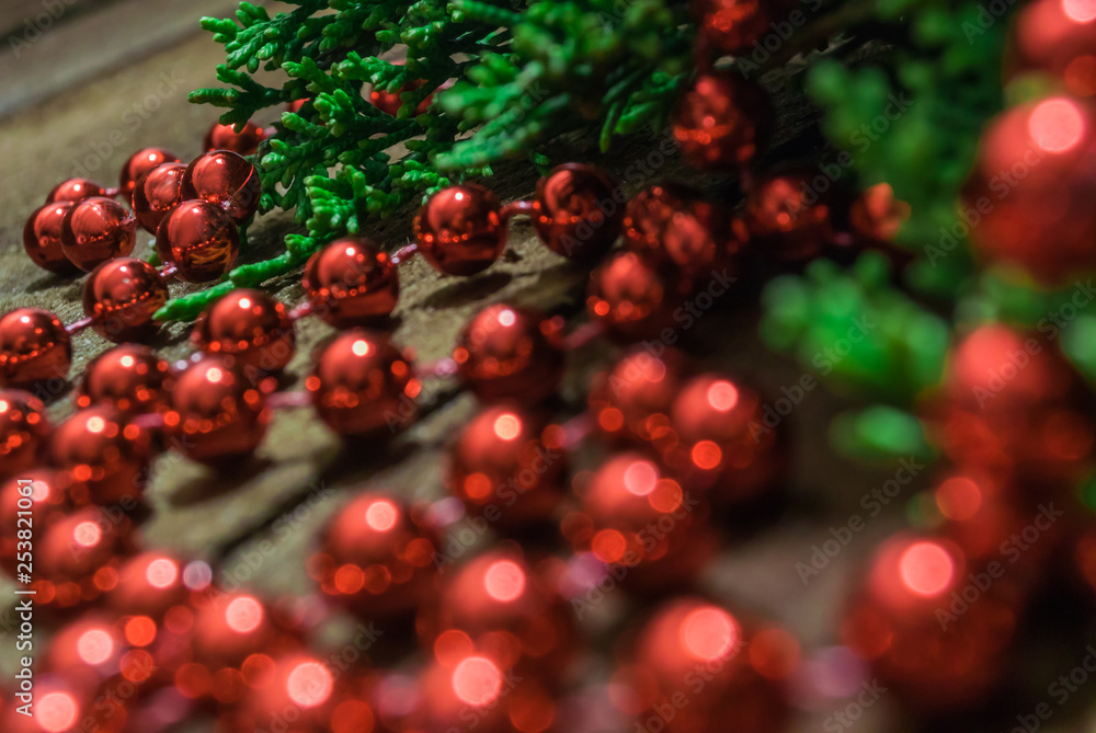 Red beads to decorate the Christmas tree close-up on a wooden background next to the coniferous branches