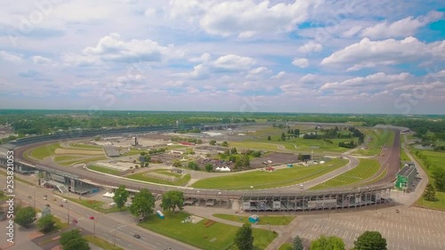Wide aerial view of the Indianapolis Motor Speedway and the Indianapolis skyline on a sunny day.