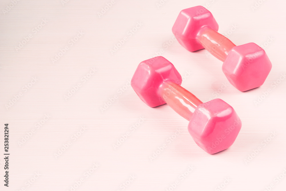 Close-up image of two pink dumbbells isolated on white wooden background Close-up image of two pink dumbbells isolated on white wooden background