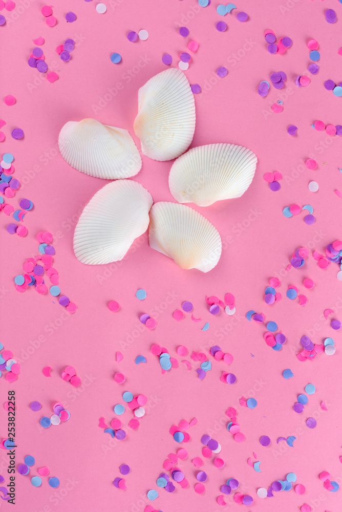 Seashell or sea shell and colorful confetti on pink textured background. Summer background, holidays sunny card, summer vacations concept.Flat lay.