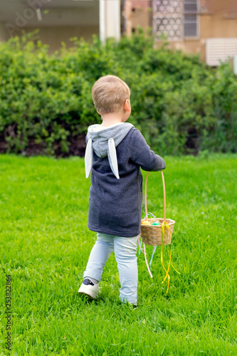 A child with a basket Easter eggs, collecting Easter eggs in a meadow with green grass