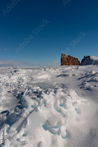 Winter sea ice with the majestic Percé Rock in the background.