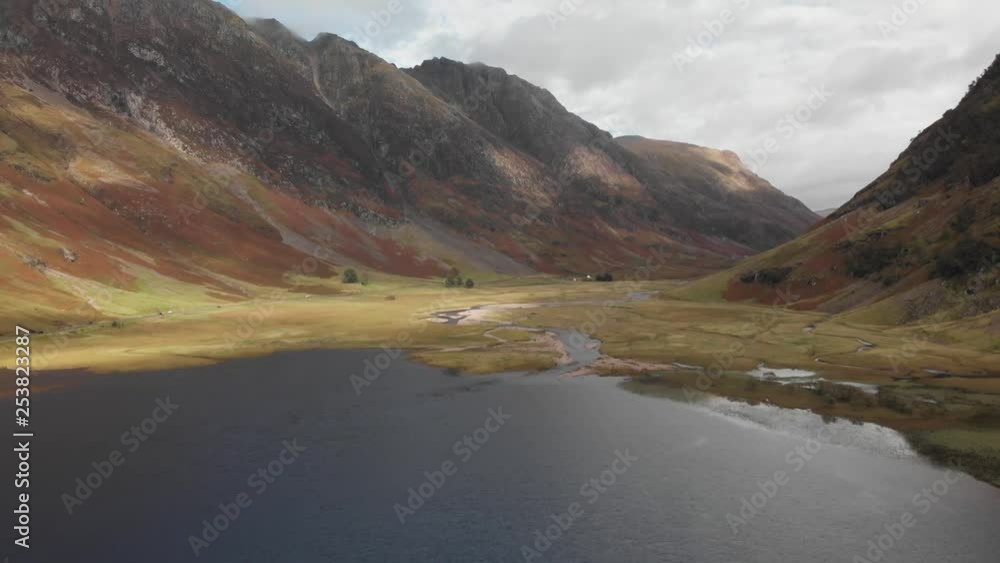 Slowly pulling back along a dark lake to reveal a Scottish highland valley in Glencoe, Scotland. Aerial, pullaway, 4K UHD. Slowly pulling back along a dark lake to reveal a Scottish highland valley in Glencoe, Scotland. Aerial, pullaway, 4K UHD.