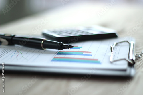 close up. pen, calculator and clipboard on wooden table. business concept