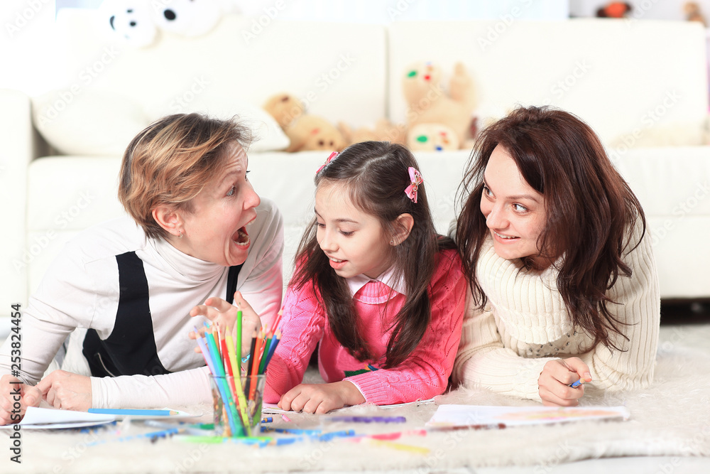 Fototapeta premium little girl draws with her mother and grandmother