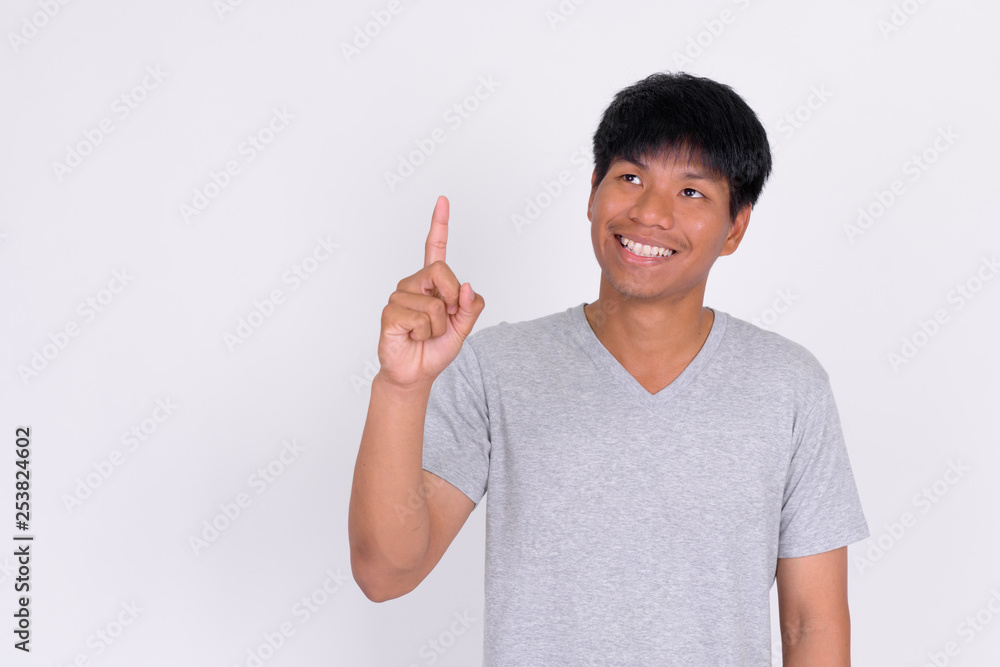 Portrait of happy young Asian man thinking and pointing up Portrait of happy young Asian man thinking and pointing up