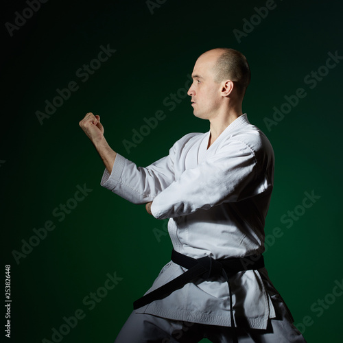 With a black belt, the athlete does formal karate exercises on a dark green background