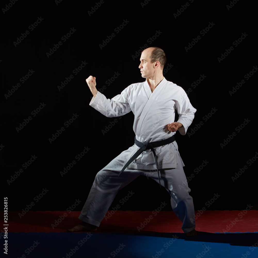 On red and blue tatami active athlete performs formal karate exercises on red and blue tatami