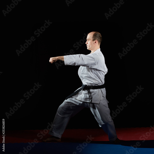On the red and blue tatami in karategi athlete doing formal exercises karate