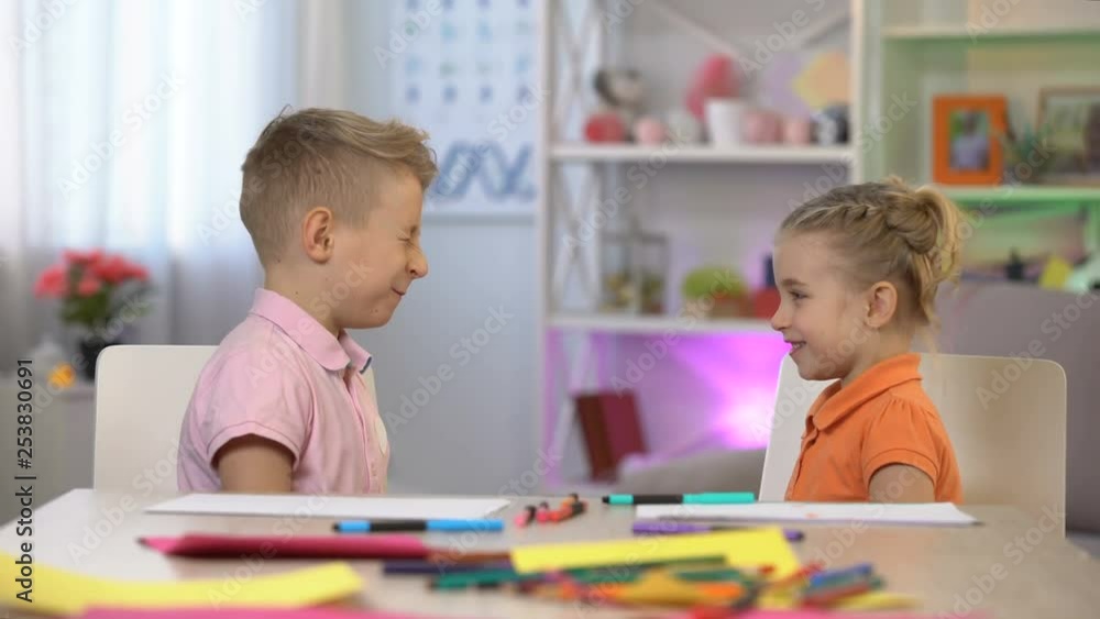 Male and female schoolkids playing together slapping face each other, having fun Male and female schoolkids playing together slapping face each other, having fun