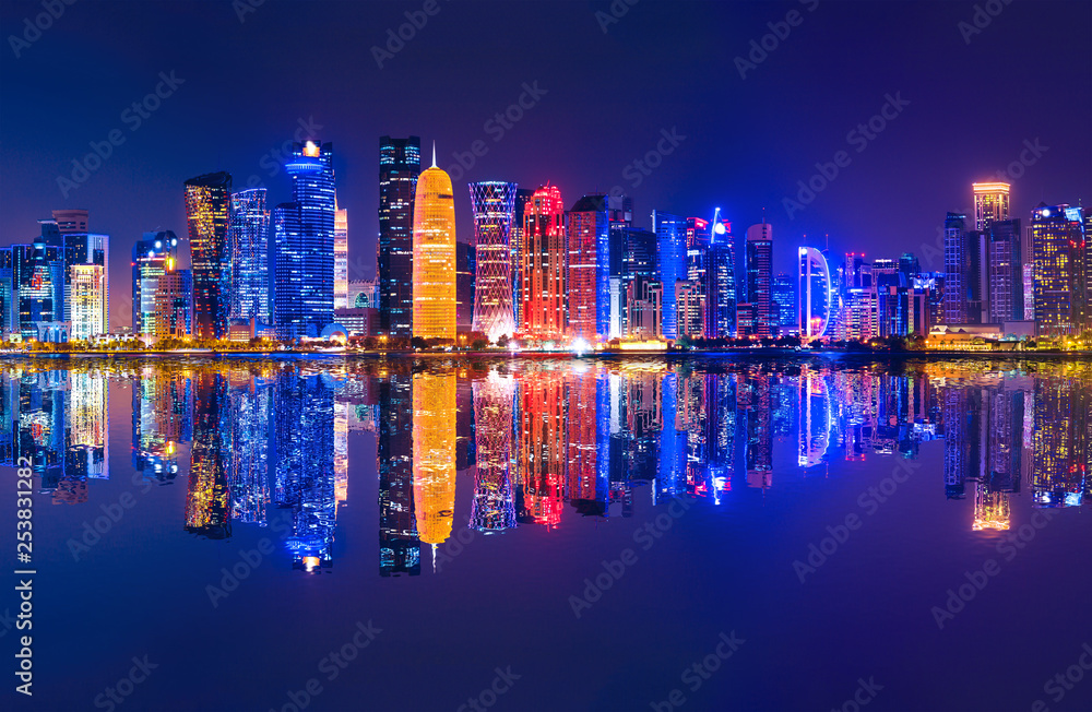 Fototapeta premium The Capital city of Qatar by night. Doha West Bay skyline reflecting in Doha Bay. Modern glassed skyscrapers of Doha in Qatar, Middle East, Arabian Peninsula in Persian Gulf. Night urban scenary.