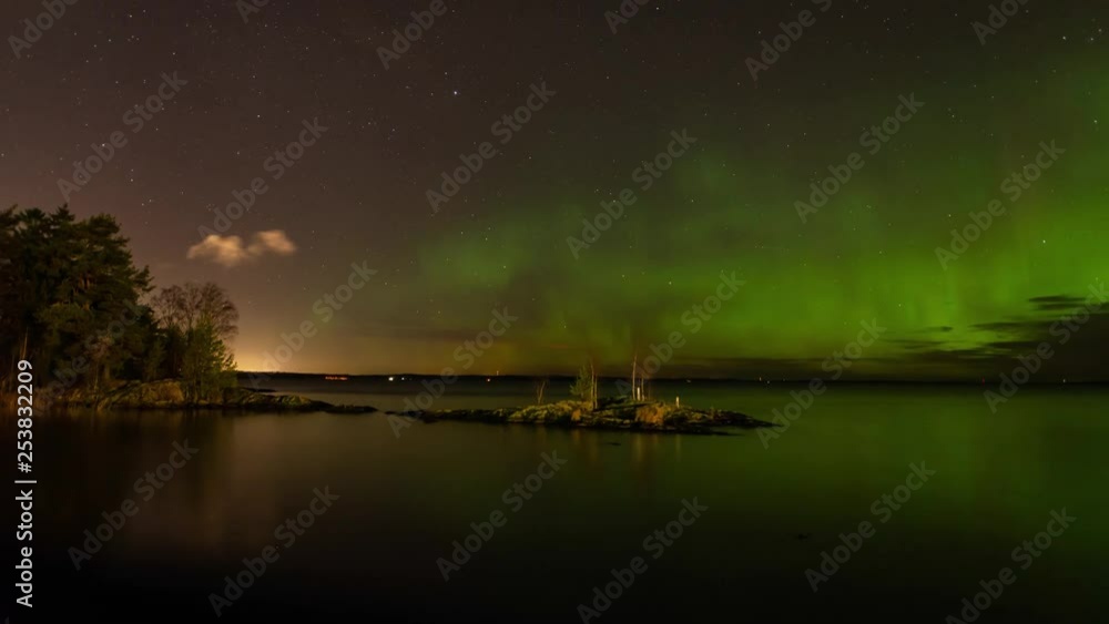 Epic time lapse of aurora borealis above lake in Tampere, Finland. Little peninsula with trees in foreground. Clouds moving. Epic time lapse of aurora borealis above lake in Tampere, Finland. Little peninsula with trees in foreground. Clouds moving.