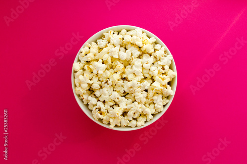 plate with popcorn on pink paper background