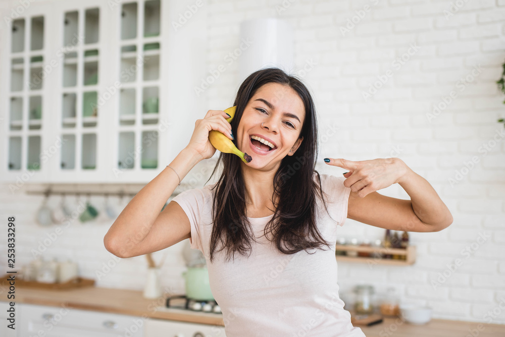 Attractive woman is holding banana like a mobile phone, funny concept Attractive woman is holding banana like a mobile phone, funny concept