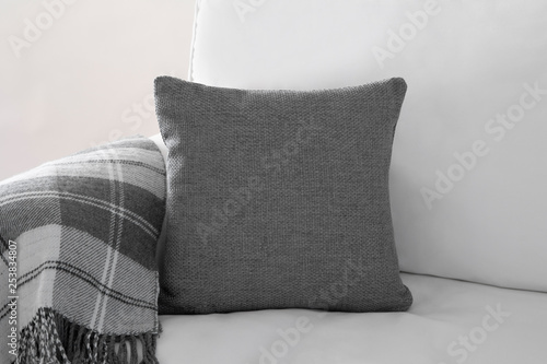 фотографія Mockup of a grey square cushion on a white sofa next to a grey plaid blanket