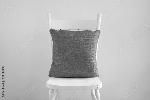 Mockup of a grey square cushion sitting on an old white dining chair. photo