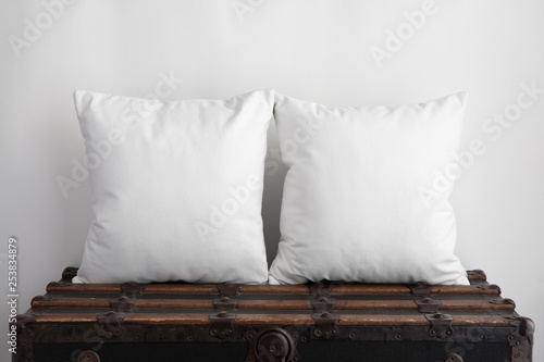 Mockup of two large white square cushions sitting on an old vintage suitcase photo