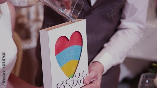 Sand ceremony at the wedding. Groom closes the tube of glass vessel filled with sand of different colors at the wedding banquet indoors.