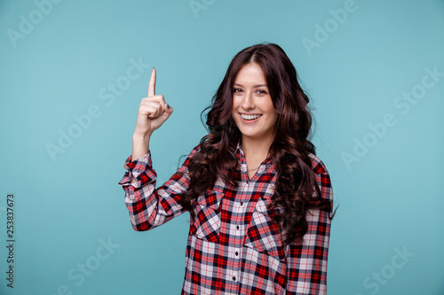 Photo of female person showing her finger up and smiling isolated over the blue backgrownd
