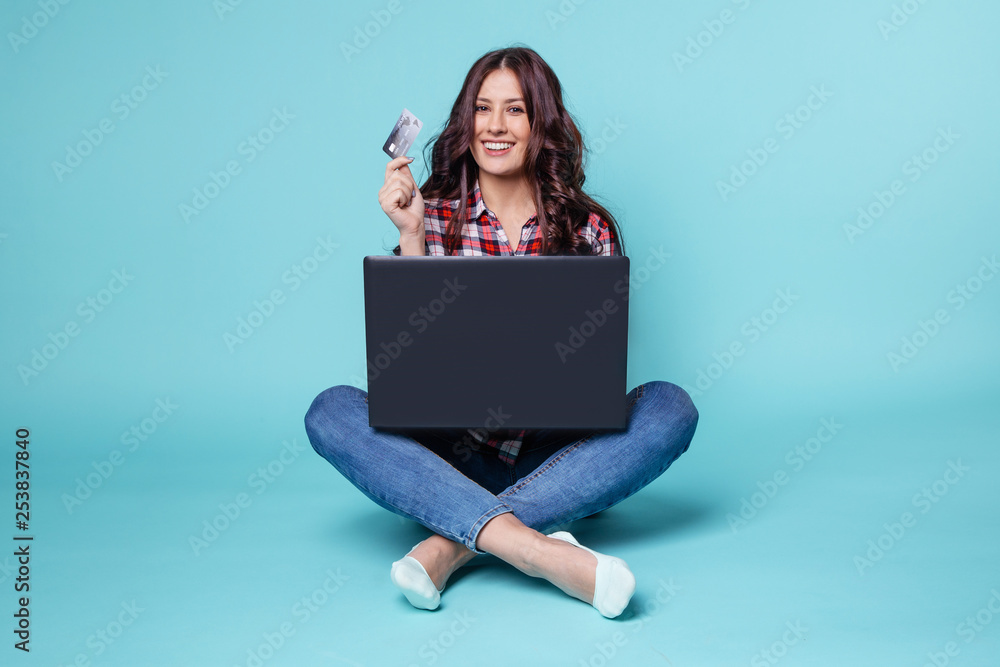 Pretty woman sitting with computer and making shopping online by credit card Pretty woman sitting with computer and making shopping online by credit card