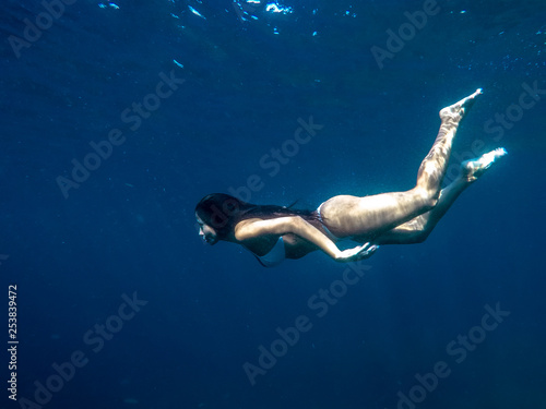 Young woman swimming underwater at sea and blue ocean