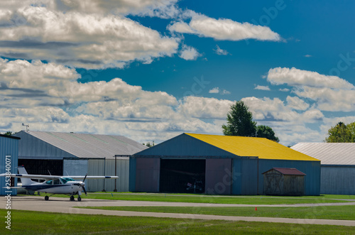 Small single engine plane in front of hangar buildings