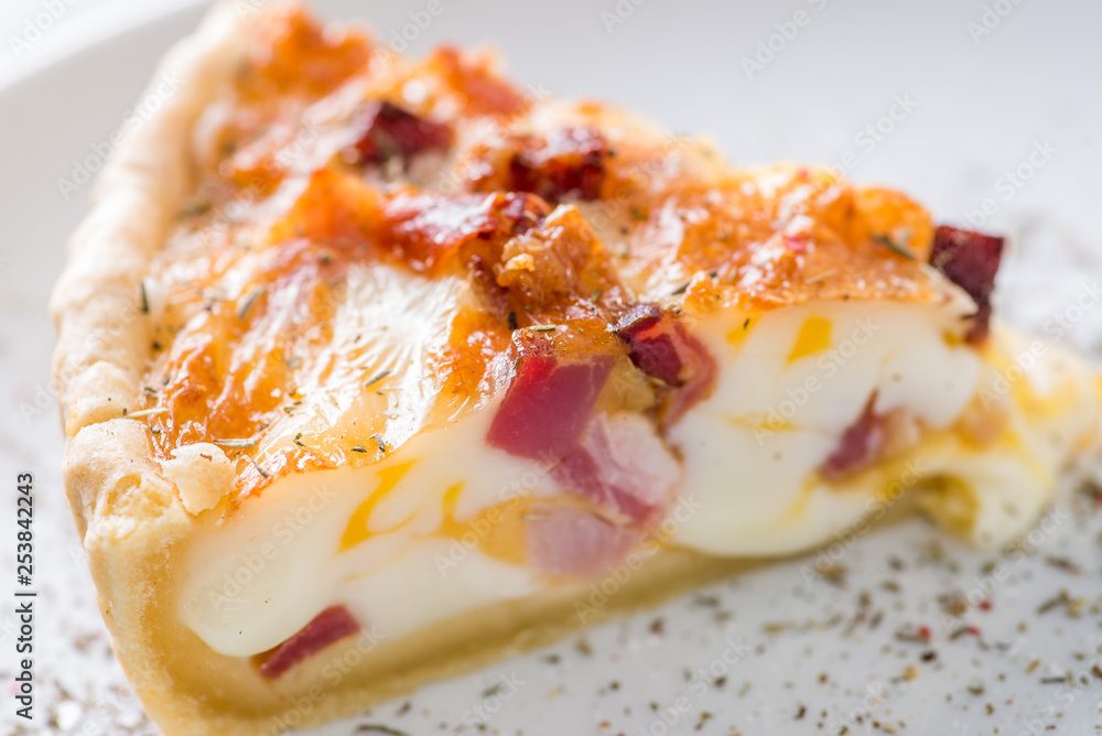 piece of quiche on a white plate served with spices piece of quiche on a white plate served with spices