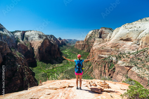 Young woman is looking at the magnificent view from Angel's landing in Zion National park. Travel and adventure concept.