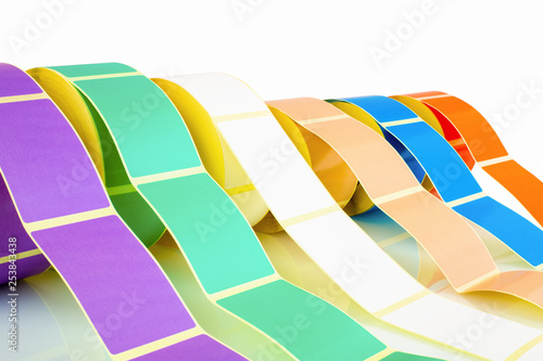 White and colored label rolls isolated on white background with shadow reflection. Color reels of labels for printers. Labels for direct thermal or thermal transfer printing. Close shot of stickers. photo