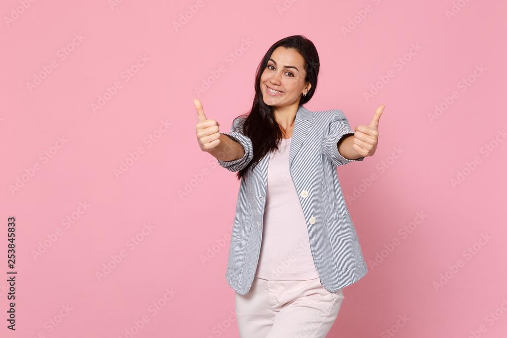 Portrait of smiling joyful young woman in striped jacket standing, showing thumbs up isolated on pink pastel wall background in studio. People sincere emotions, lifestyle concept. Mock up copy space. Portrait of smiling joyful young woman in striped jacket standing, showing thumbs up isolated on pink pastel wall background in studio. People sincere emotions, lifestyle concept. Mock up copy space.