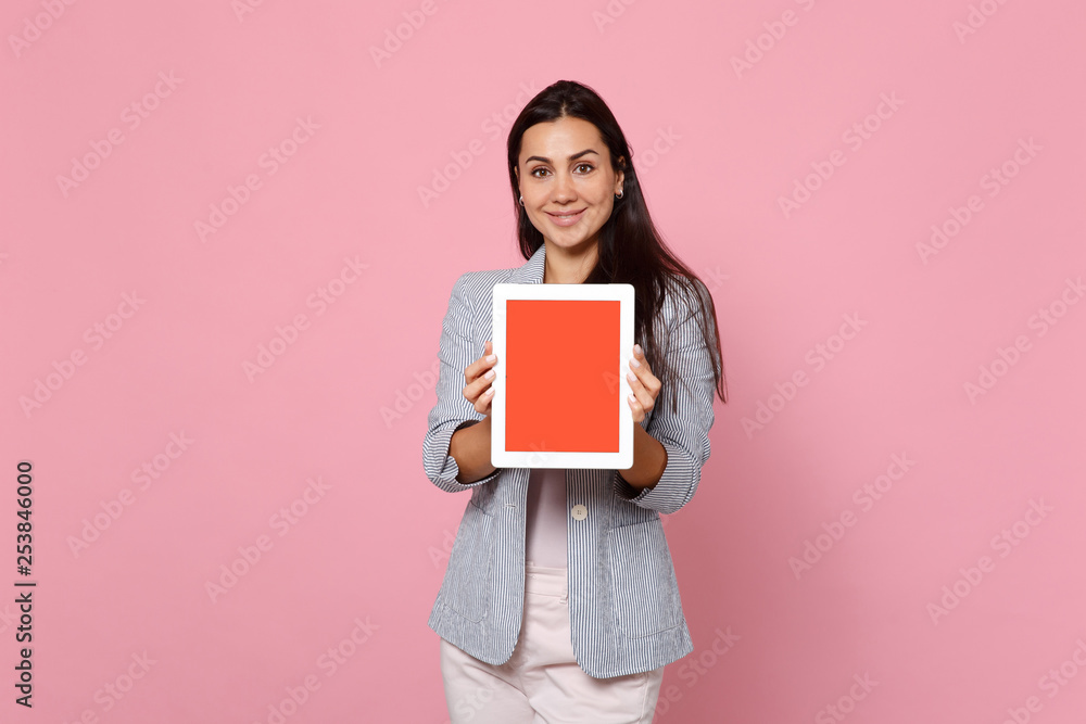 Portrait of smiling young woman in striped jacket holding tablet pc computer with blank empty screen isolated on pink pastel background. People sincere emotions lifestyle concept. Mock up copy space. Portrait of smiling young woman in striped jacket holding tablet pc computer with blank empty screen isolated on pink pastel background. People sincere emotions lifestyle concept. Mock up copy space.