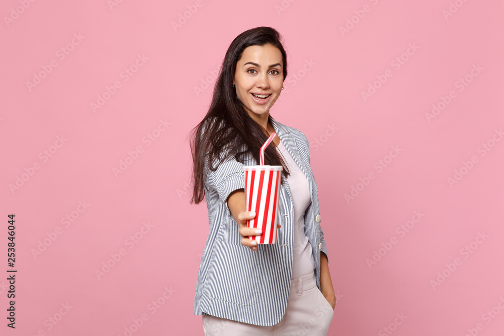 Portrait of attractive cheerful young woman in striped jacket hold plastic cup of cola or soda isolated on pink pastel wall background. People sincere emotions, lifestyle concept. Mock up copy space. Portrait of attractive cheerful young woman in striped jacket hold plastic cup of cola or soda isolated on pink pastel wall background. People sincere emotions, lifestyle concept. Mock up copy space.