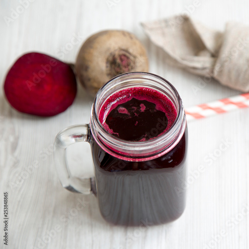 Beetroot juice in glass jar over white wooden background, side view. Close-up.