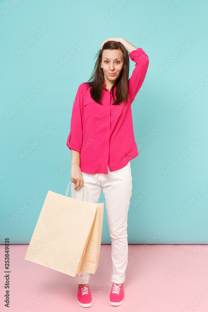 Full length portrait smiling young woman in rose shirt blouse, white pants hold shopping bags isolated on bright pink blue pastel wall background studio. Fashion lifestyle concept. Mock up copy space. Full length portrait smiling young woman in rose shirt blouse, white pants hold shopping bags isolated on bright pink blue pastel wall background studio. Fashion lifestyle concept. Mock up copy space.