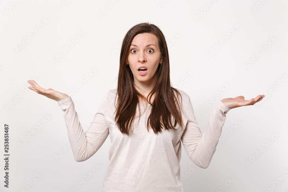 Portrait of shocked perplexed young woman in light clothes spreading and pointing hands aside isolated on white background in studio. People sincere emotions, lifestyle concept. Mock up copy space. Portrait of shocked perplexed young woman in light clothes spreading and pointing hands aside isolated on white background in studio. People sincere emotions, lifestyle concept. Mock up copy space.