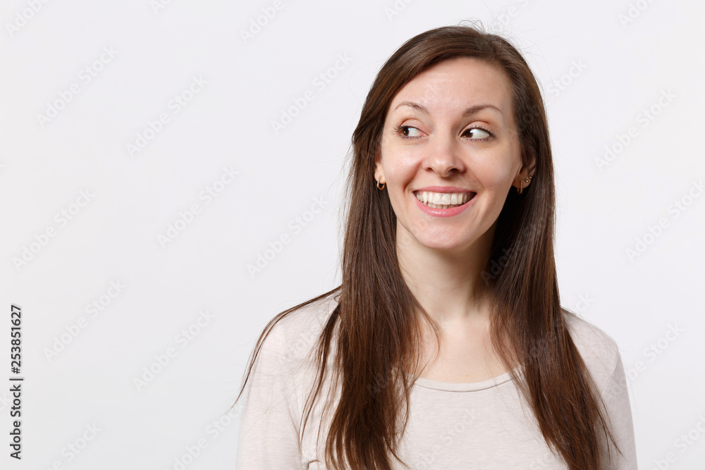 Portrait of smiling joyful pretty young woman in light clothes standing and looking aside isolated on white wall background in studio. People sincere emotions lifestyle concept. Mock up copy space. Portrait of smiling joyful pretty young woman in light clothes standing and looking aside isolated on white wall background in studio. People sincere emotions lifestyle concept. Mock up copy space.