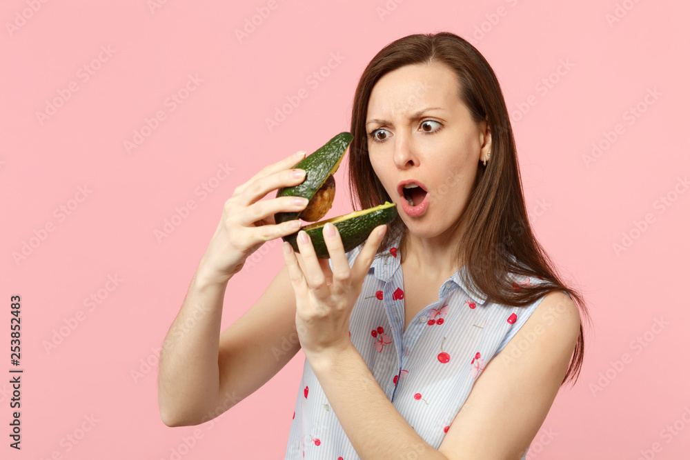Shocked woman in summer clothes keeping mouth open holding two halfs of fresh ripe avocado fruit isolated on pink pastel background. People vivid lifestyle relax vacation concept. Mock up copy space. Shocked woman in summer clothes keeping mouth open holding two halfs of fresh ripe avocado fruit isolated on pink pastel background. People vivid lifestyle relax vacation concept. Mock up copy space.
